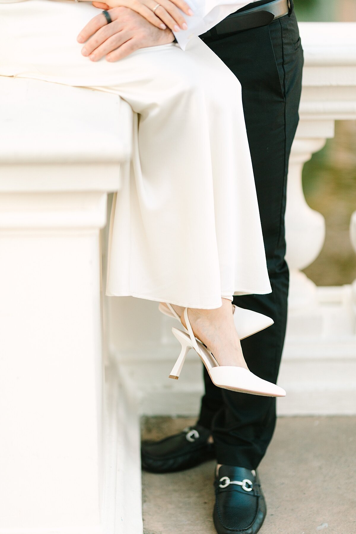 Close up during engagement session of bride's pointed toe white heels.