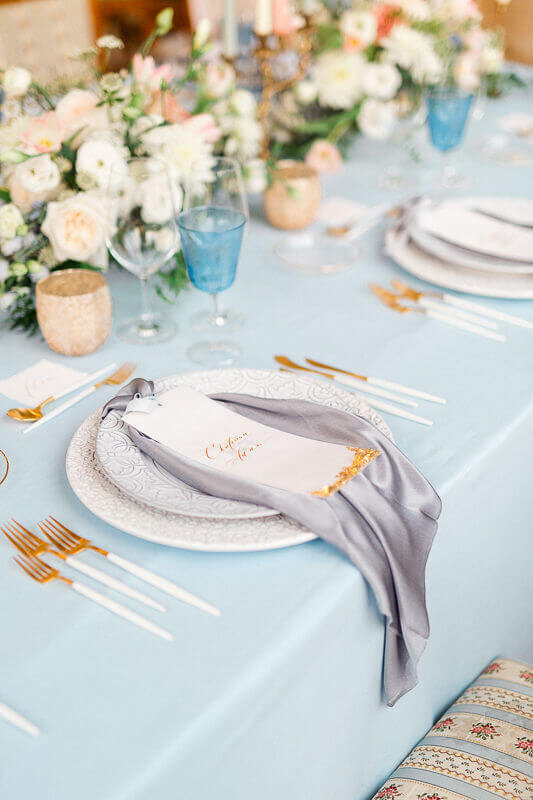 Table setting with plates from Bordalo Pinheiro and silk napkin with calligraphy wedding menu in Bussaco Palace Portugal