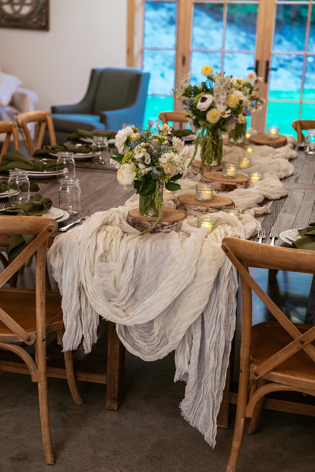 Cozy indoor elopement dinner setup featuring flowing ivory fabric, floral centerpieces, and soft candlelight for an intimate celebration.