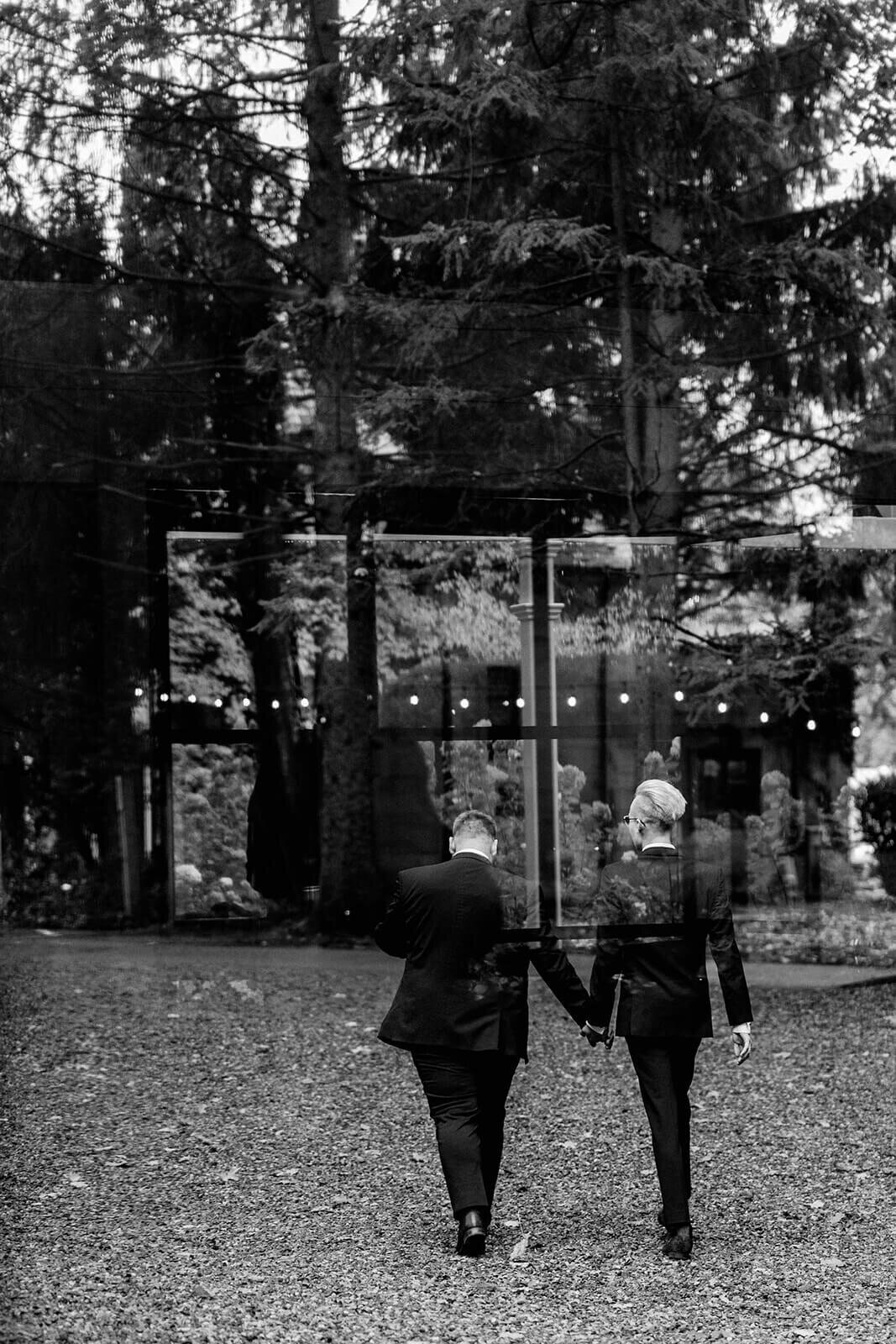 two grooms holding hands and walking at Greencrest Manor in Michigan
