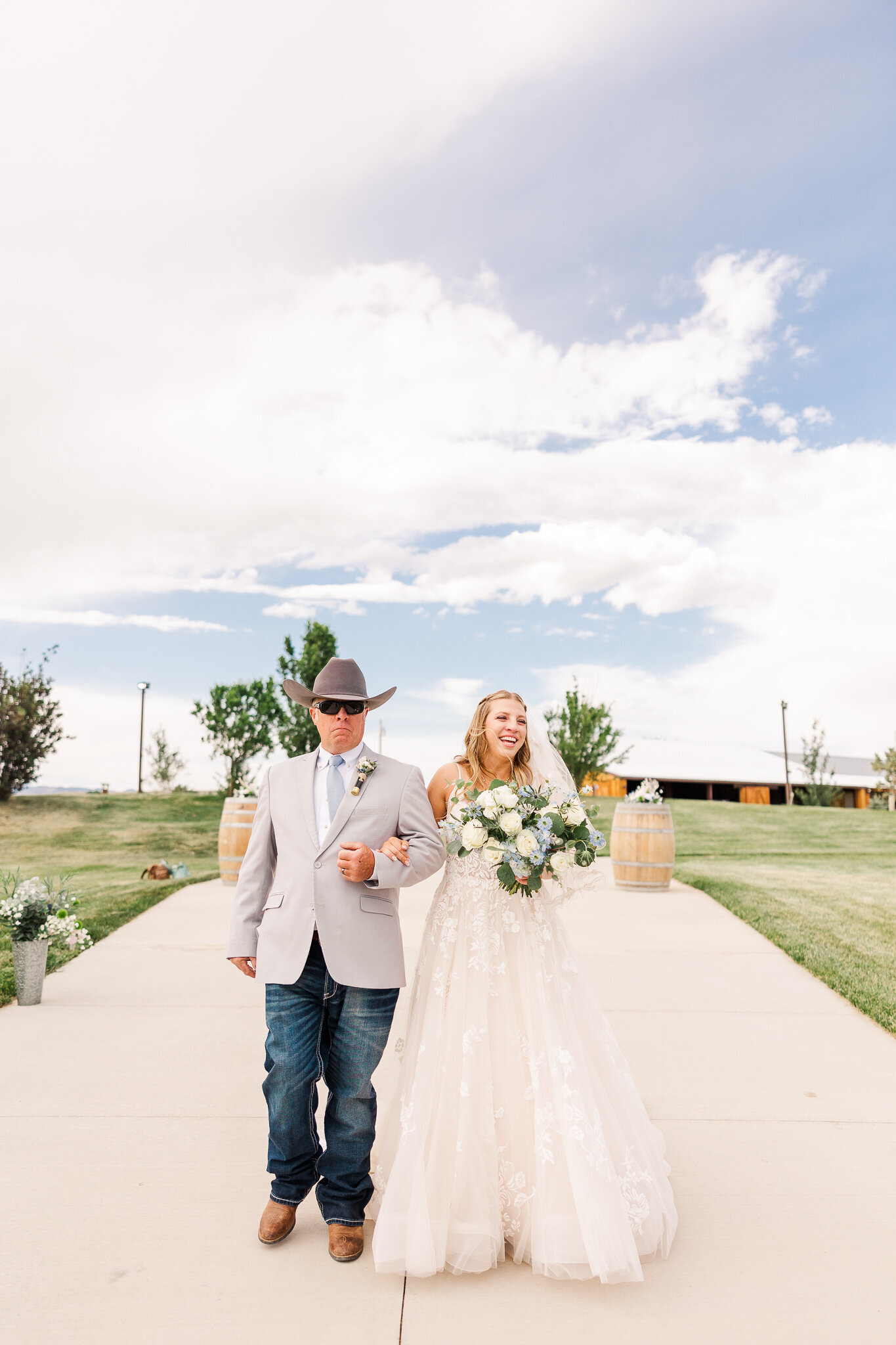 Another perspective of the bride and her father walking toward the ceremony with mountain views in the background.
