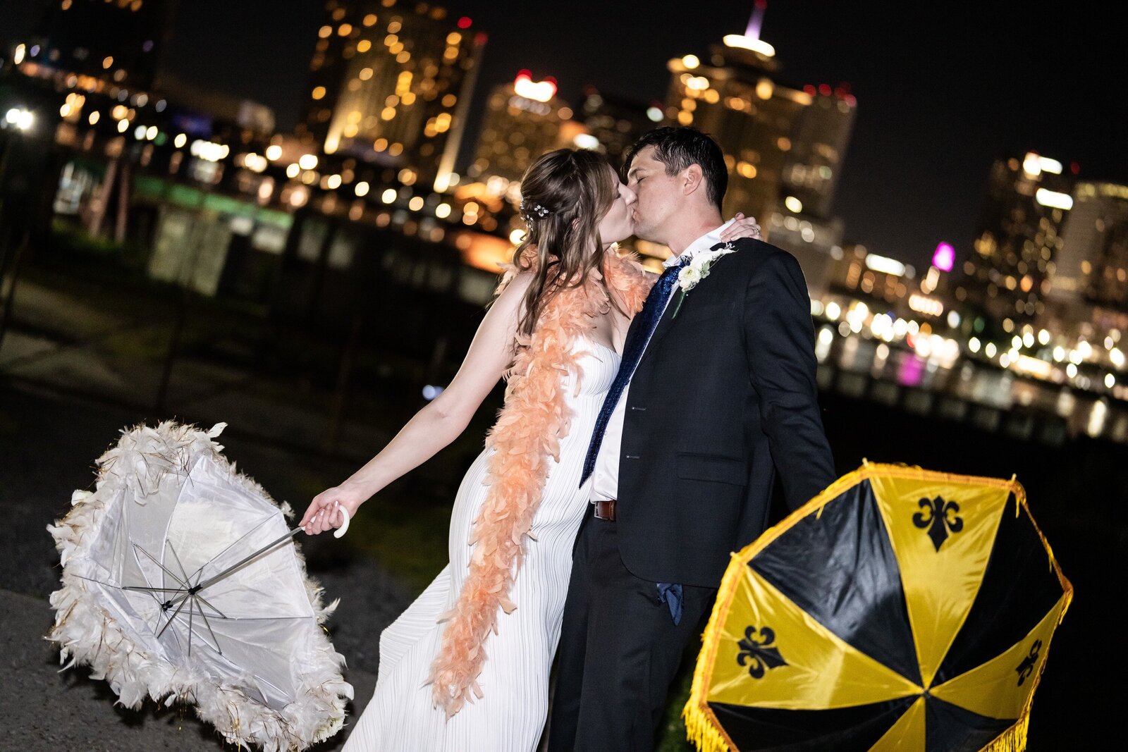 Bride and groom kiss with New Orleans city skyline in background