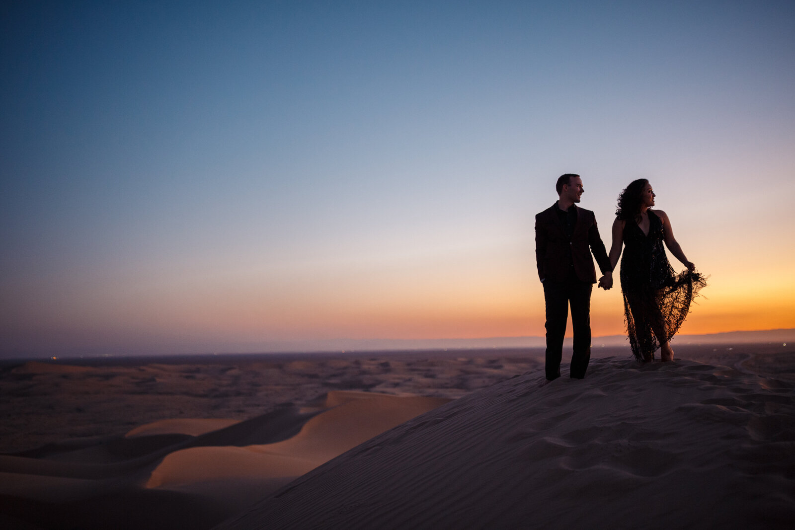 couple holding hands in the algodones sand dunes at sunset