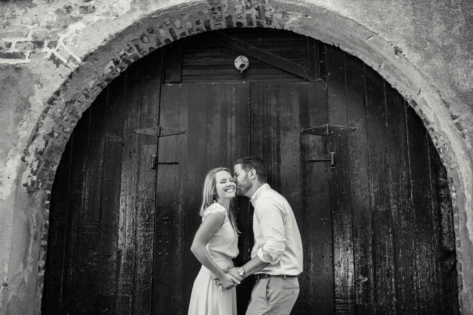 Engaged couple stand under arched door in Dueler's Alley, Downtown Charleston, South Carolina