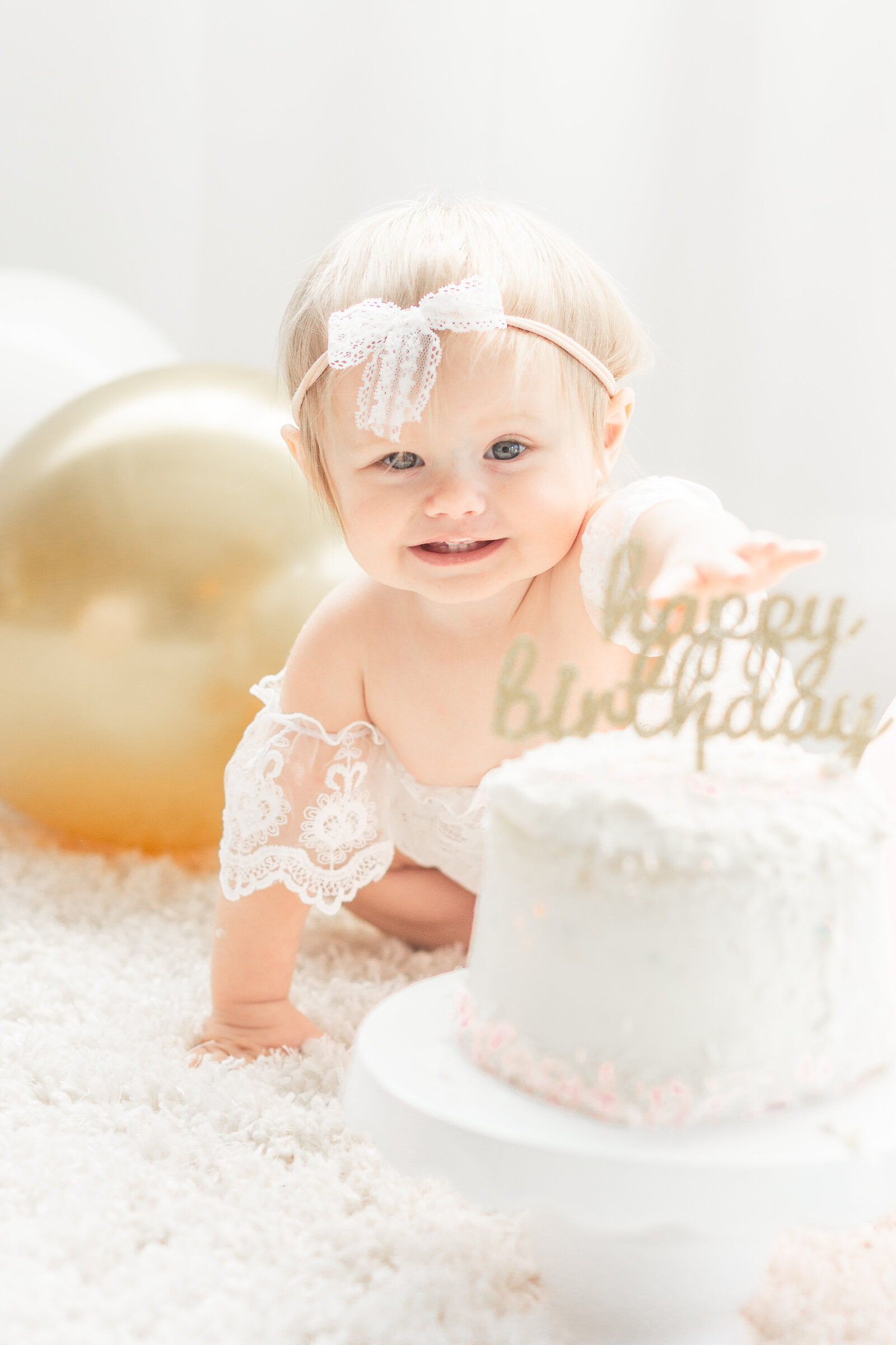 Plymouth Michigan newborn photographer captures baby girl going for her first birthday cake at Studio Neue in Plymouth Michigan