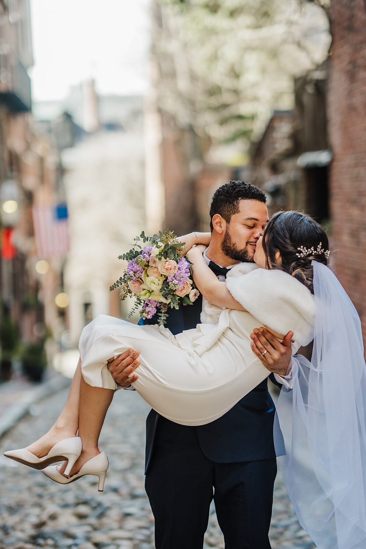 groom picks up bride to kiss her on acorn street in boston