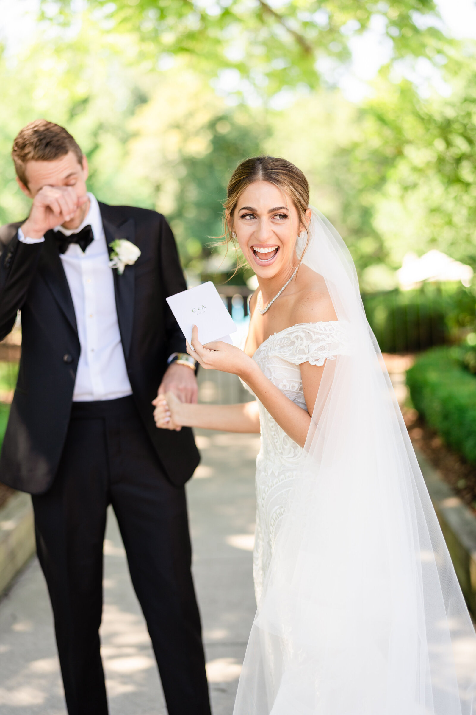 Bride laughs as her groom wipes away a tear during their first look