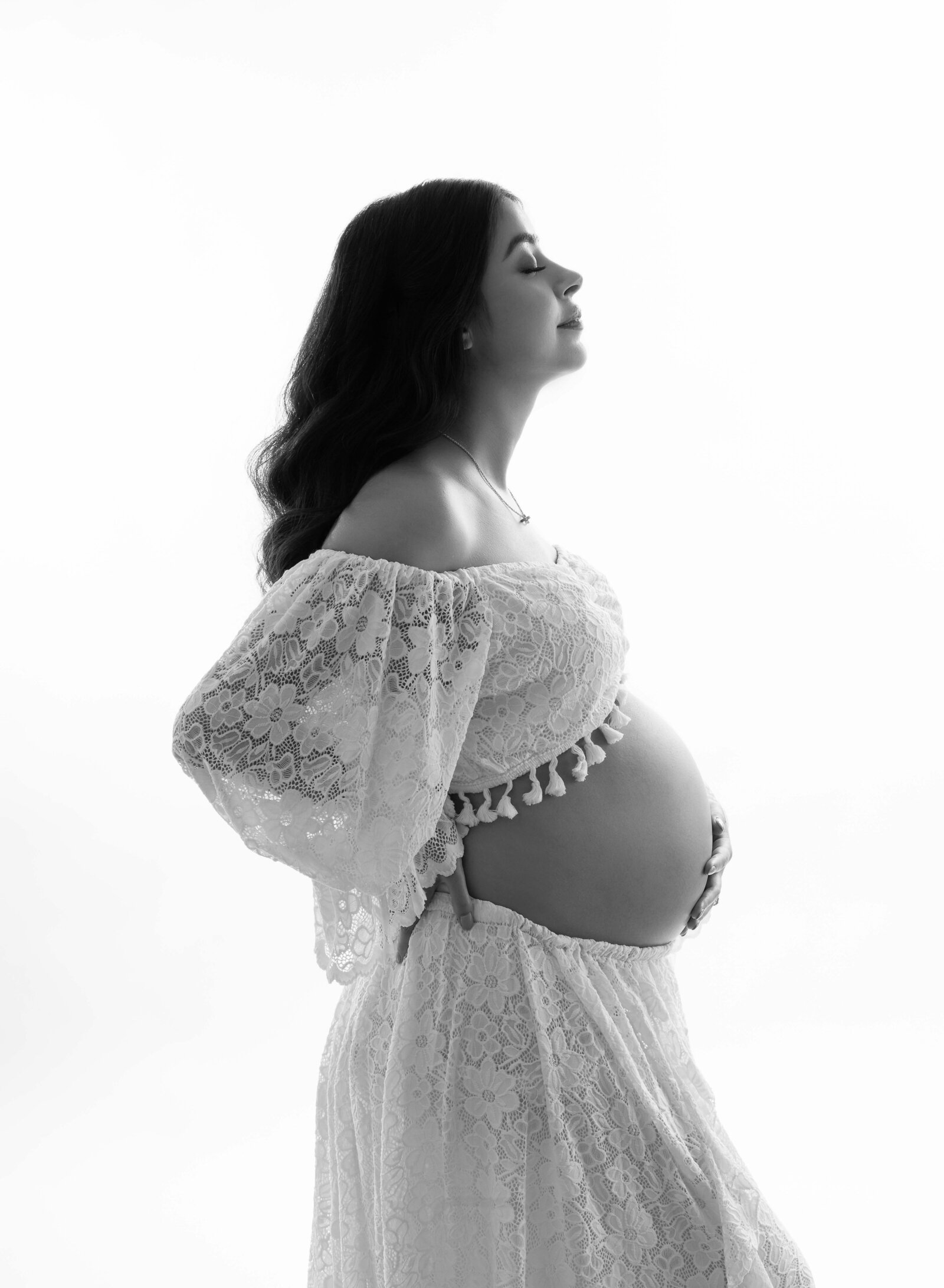 B&W photo of Mom holding baby bump and looking up with eyes closed thinking of baby to be. Pregnancy photo taken by Jenni. Nikki Photography at Atlanta Photo Studio. 