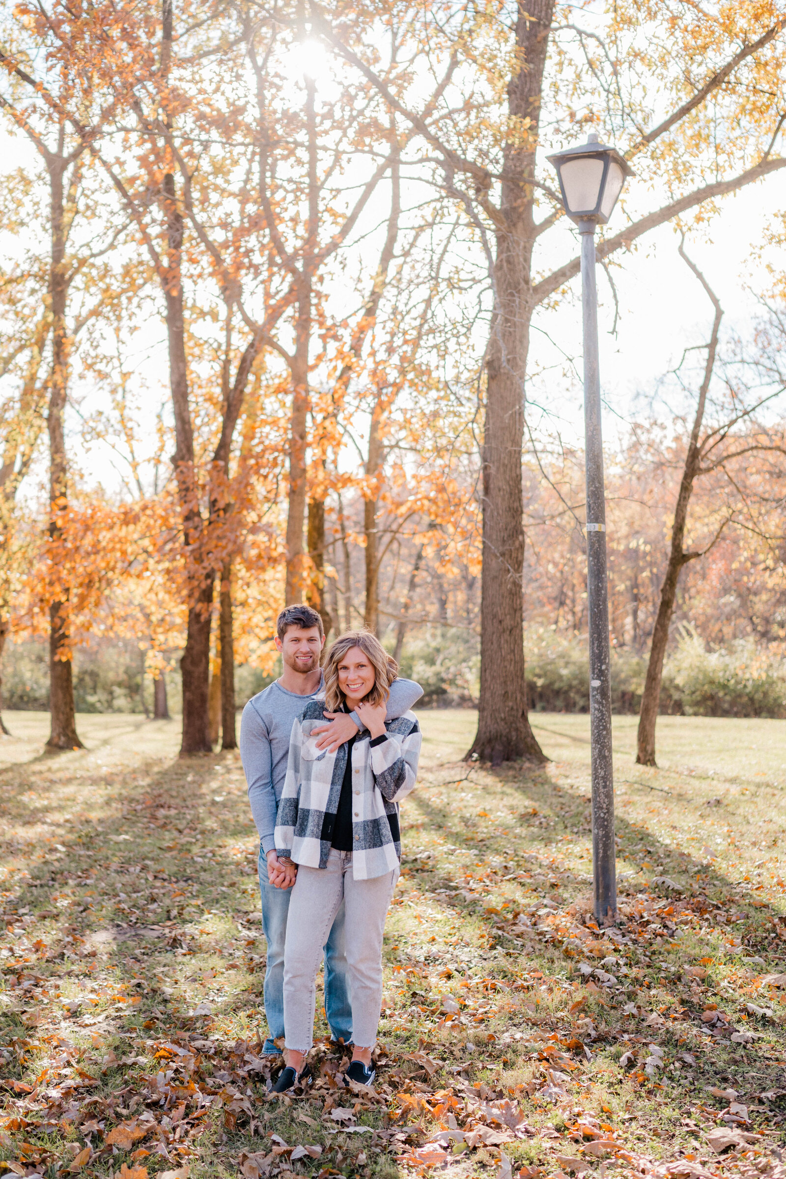 Couple poses for the camera outside with the fall leaves.