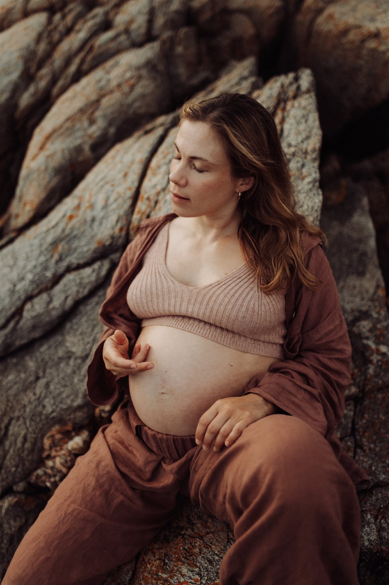 en gravid mamma smeker hennes mage iklädd linnebyxor och linneskjorta