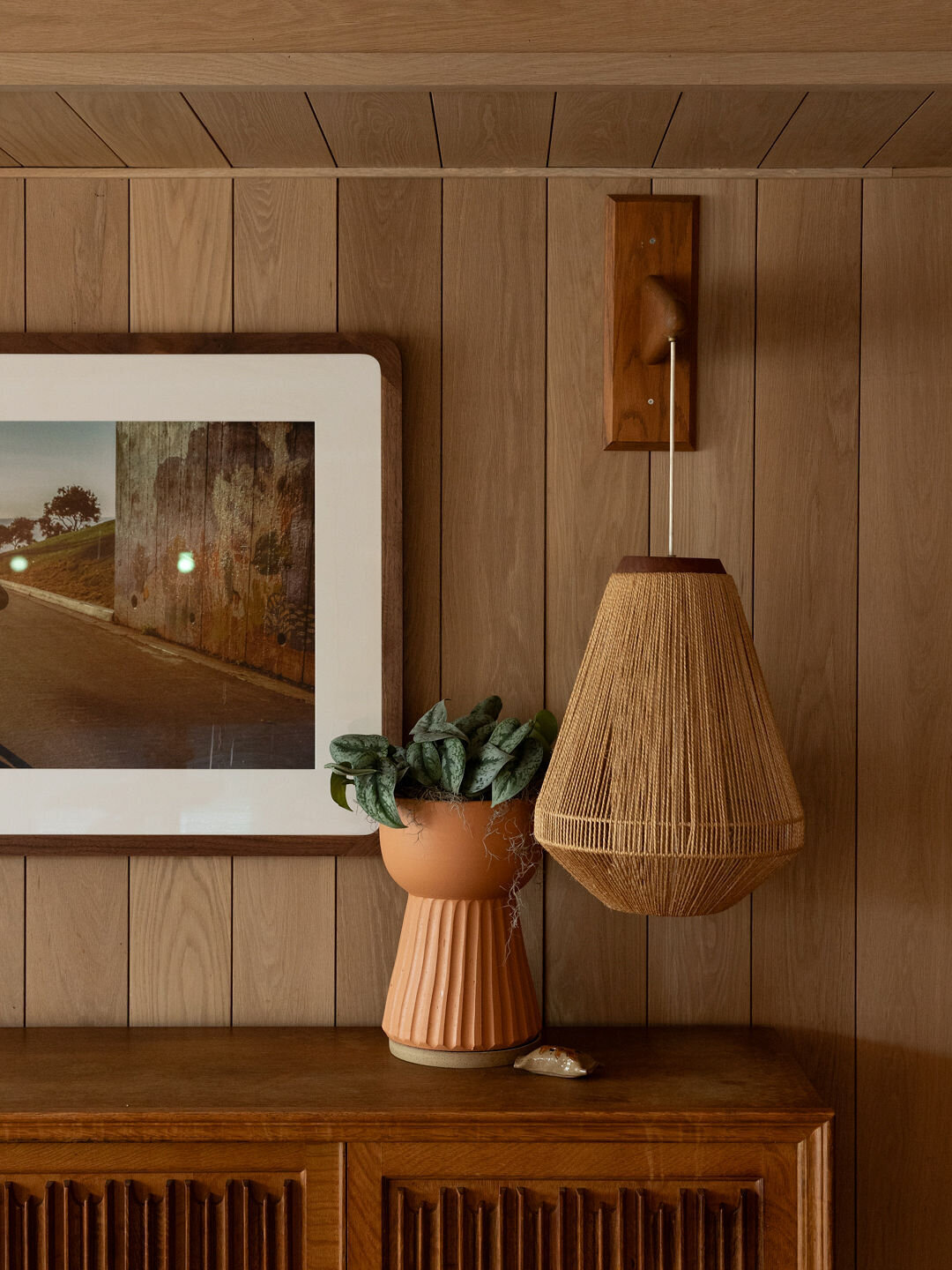Mid century modern hotel decor with light wooden wall paneling and rattan lamp at Ryder Hotel Charleston