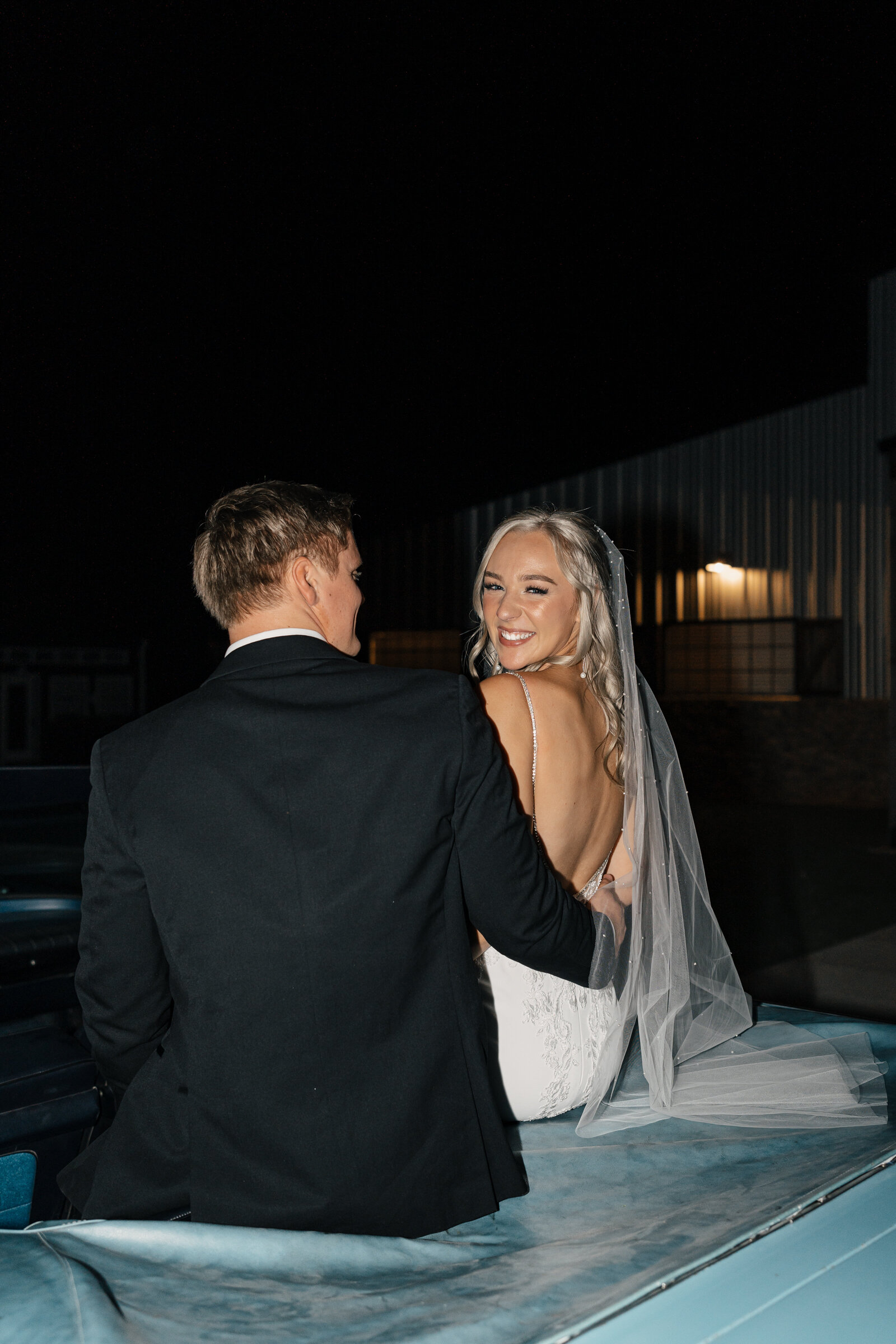 Bride and groom driving off in a classic getaway car after their destination wedding