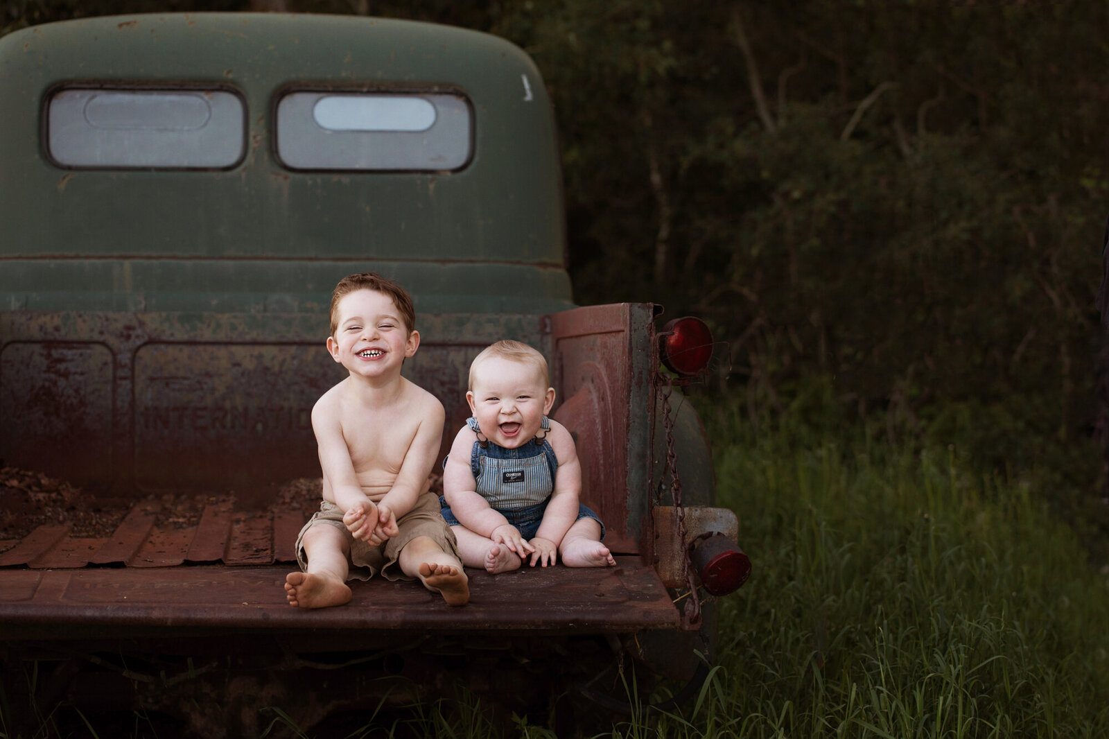 two boys sitting on the back of a truck