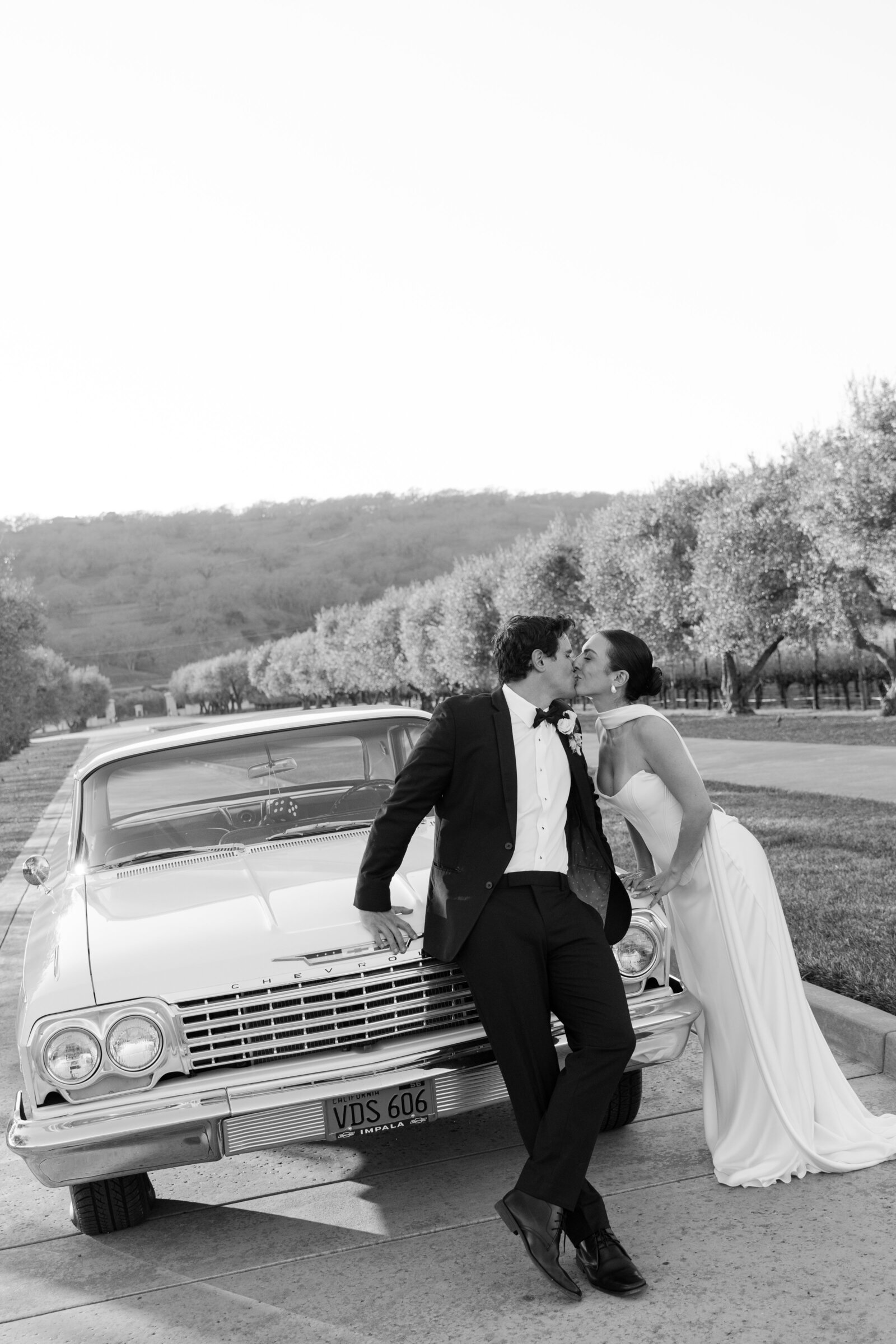 Elegant bride and groom posing by a vintage car surrounded by vineyards out in Napa, CA captured by a Northern California photographer MVF Portraits 