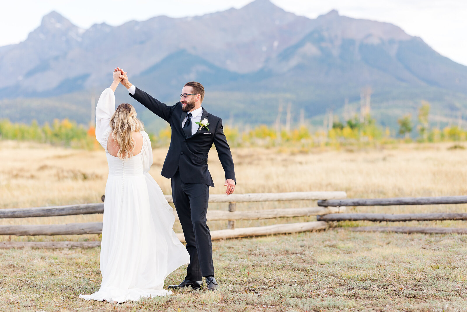 Groom spinning his bride with mountain views in the background at a private wedding near the Dallas Divide in Montrose, Colorado, radiating joy and movement.