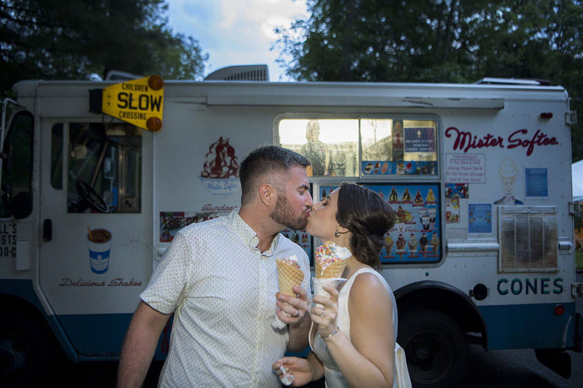 A couple kissing as they both hold ice cream cones 