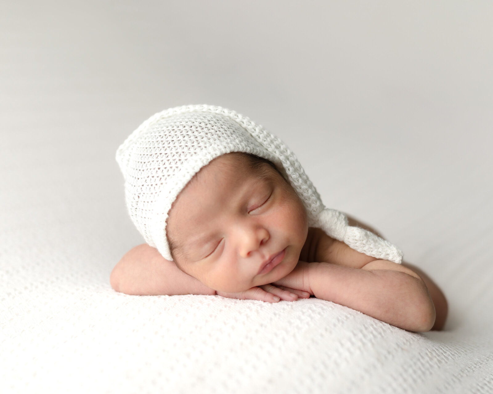 newborn baby boy in white hat posed for studio portraits cleveland newborn photographer