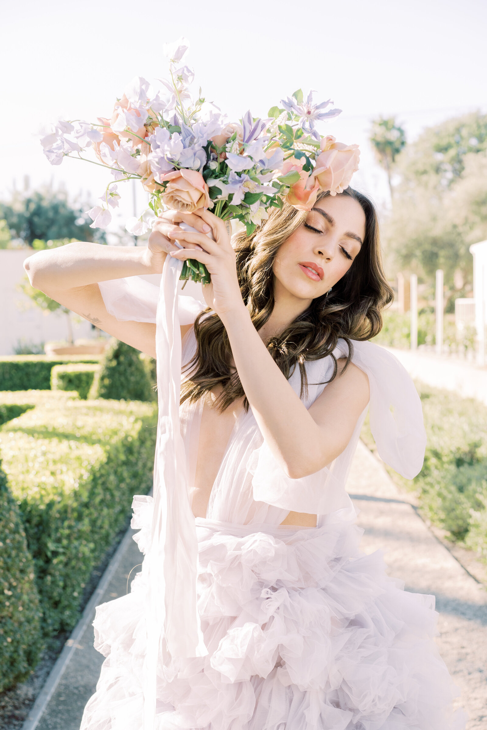 Portrait of bride in a lavender gown holding a bouquet in a garden outdoors