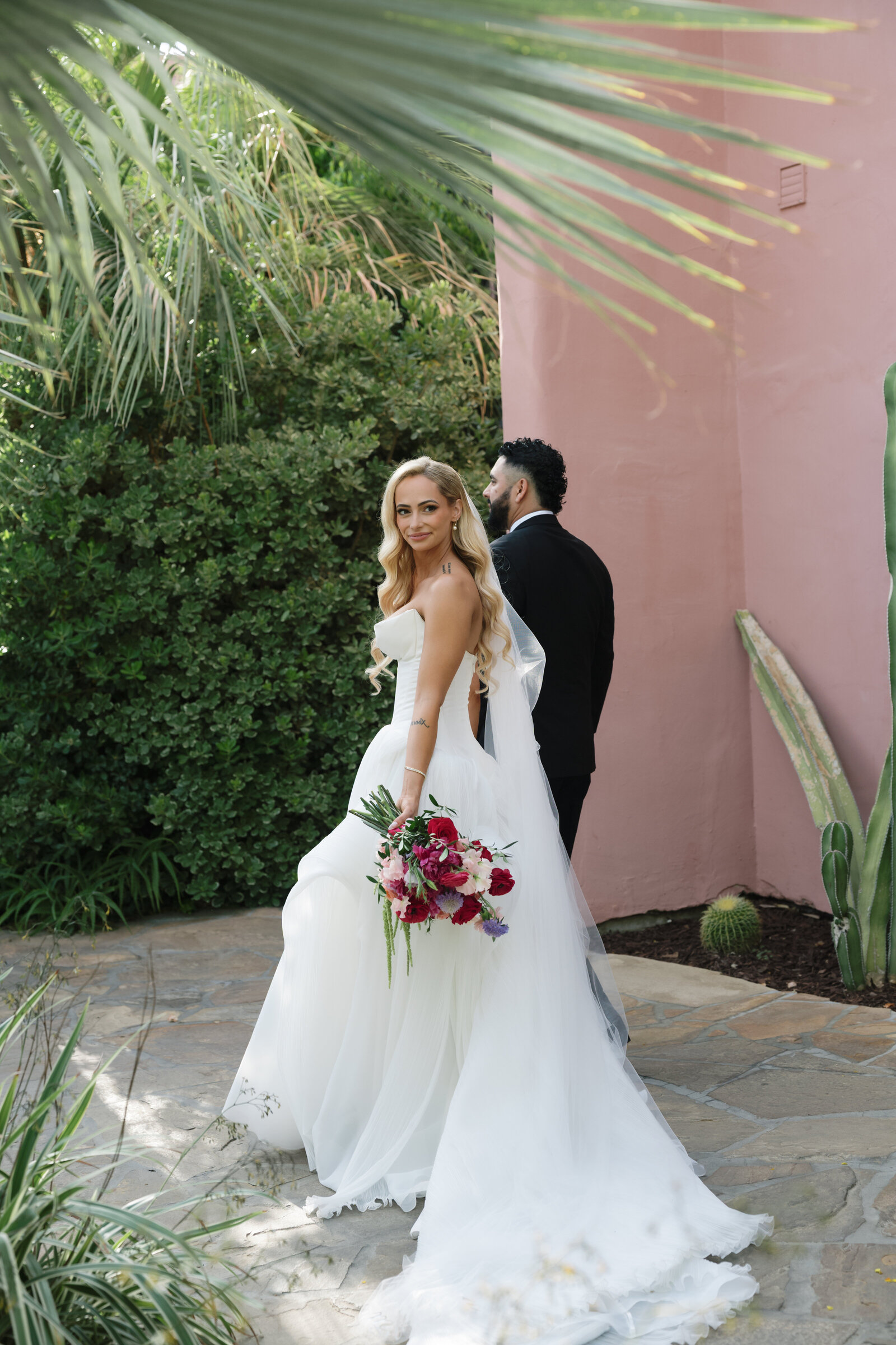 Bride and groom walking inside Sands Hotel in Palm Springs, holding a colorful floral bouquet, captured by a Palm Springs photographer MVF Portraits 