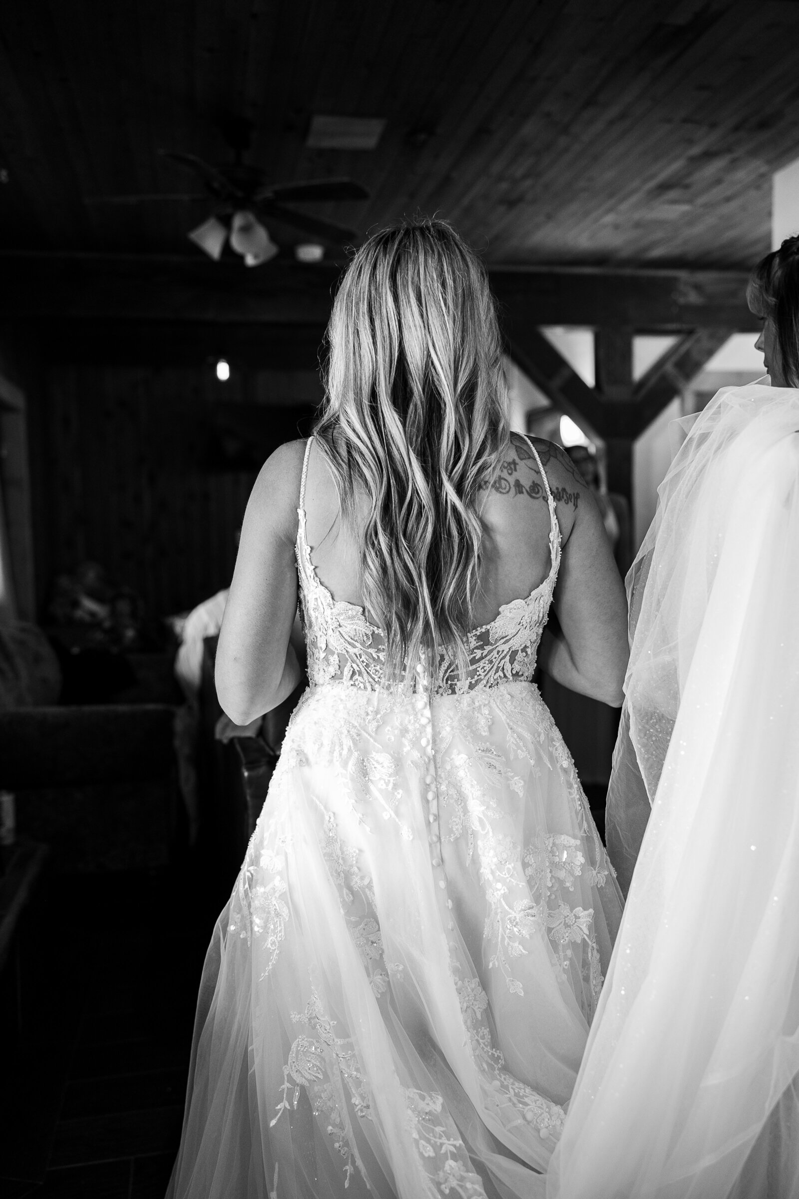 Back of brides dress as her maid of honor helps her fix her train in Arrowhead Colorado