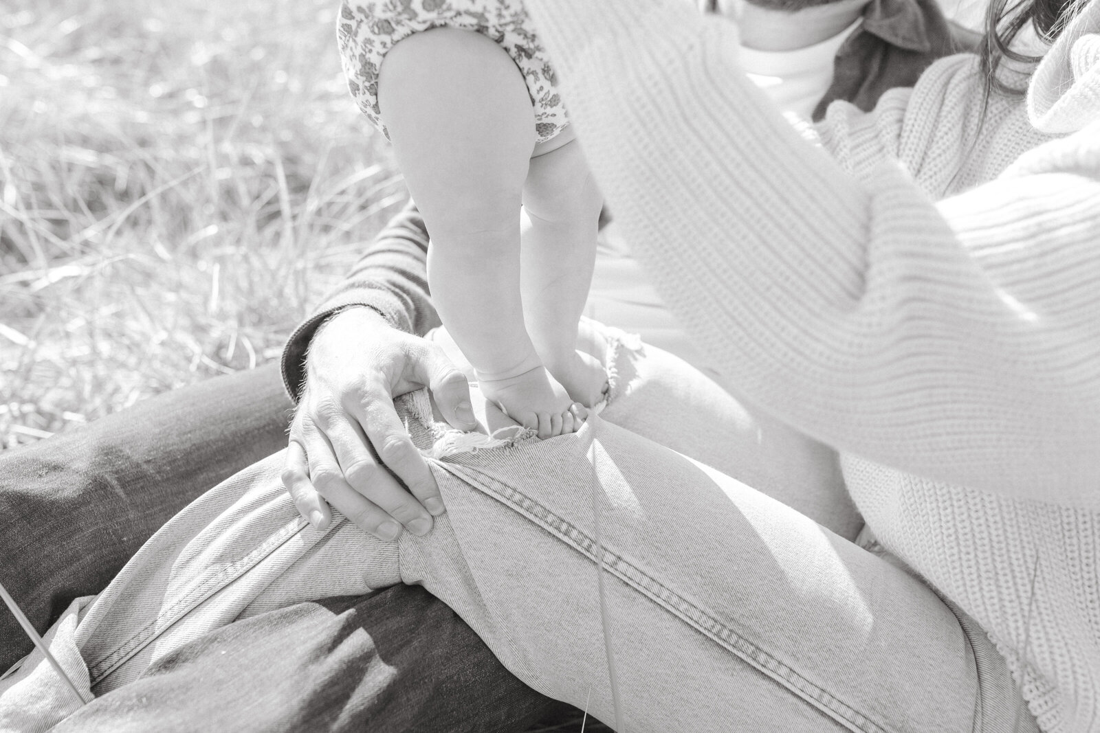 Close up of baby standing on parents lap at Seaside beach on the Oregon Coast.