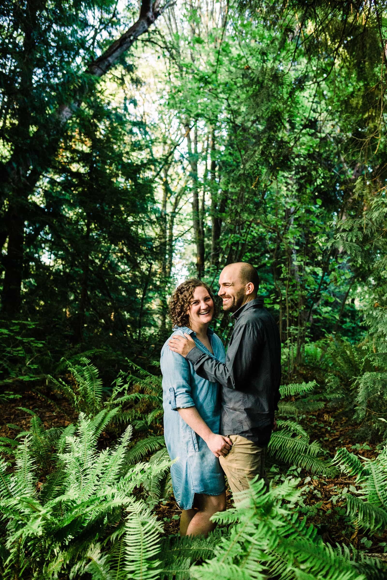 Couple standing in Seattle fern forest area smiling