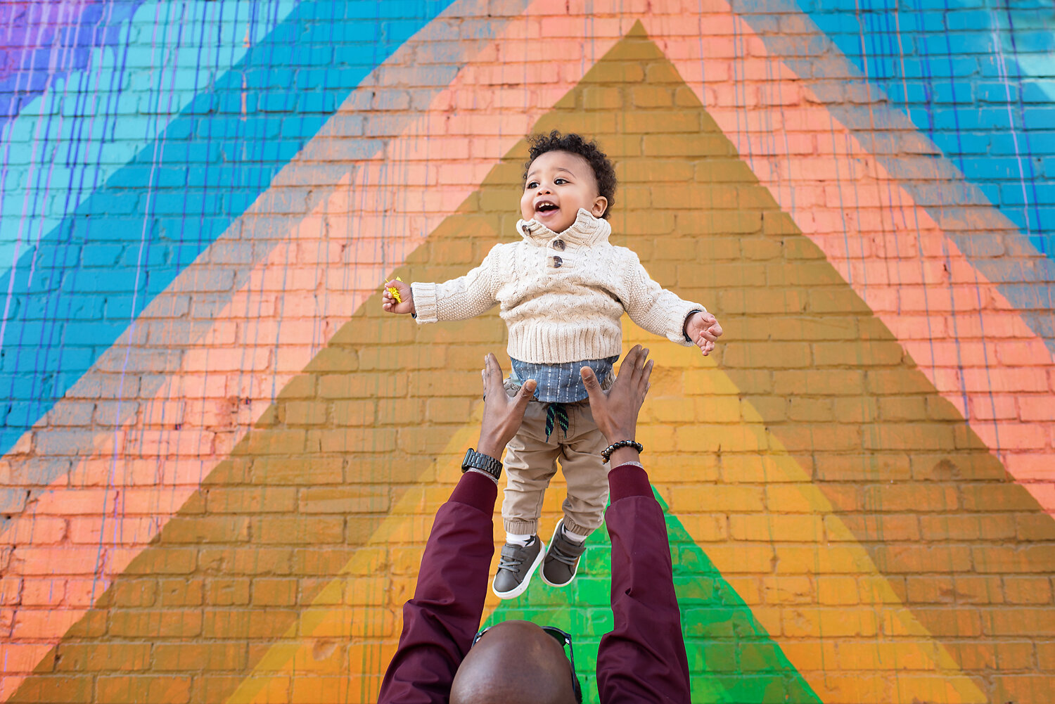 One year old boy flying in the air in front of a colorful wall in Deep Ellum, TX