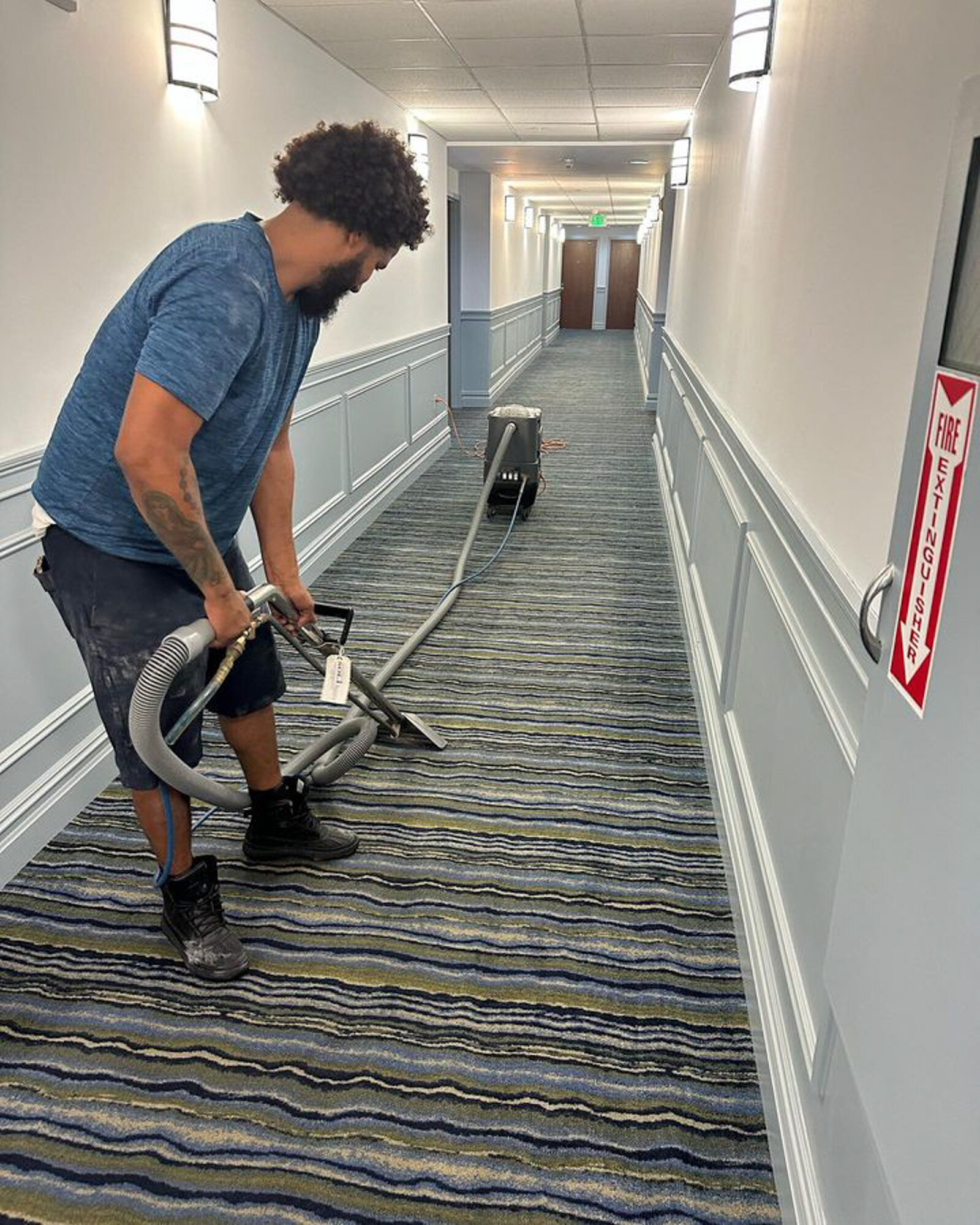 Worker deep cleaning a hotel hallway carpet