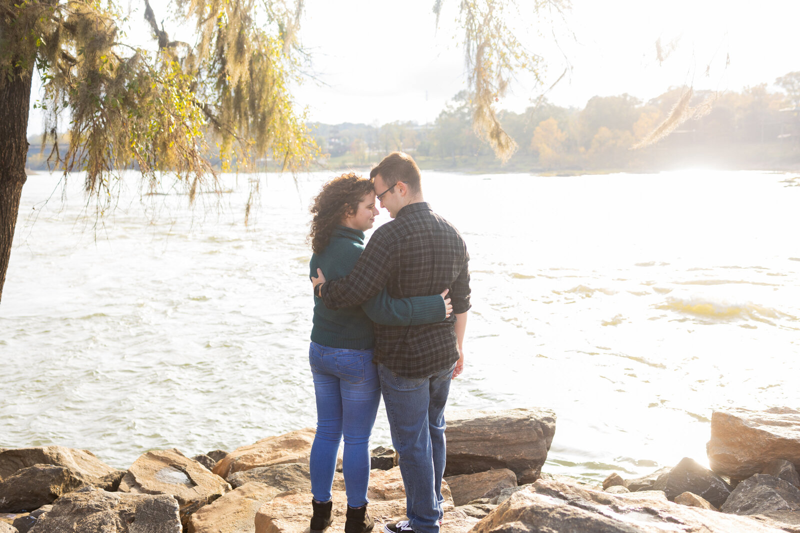 couple-holding-each-other-along-waterfront-at-sunset