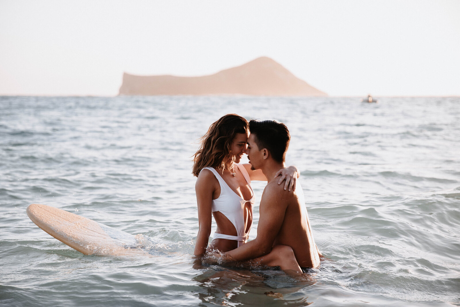couple-sitting-on-surfboard-kissing-in-ocean