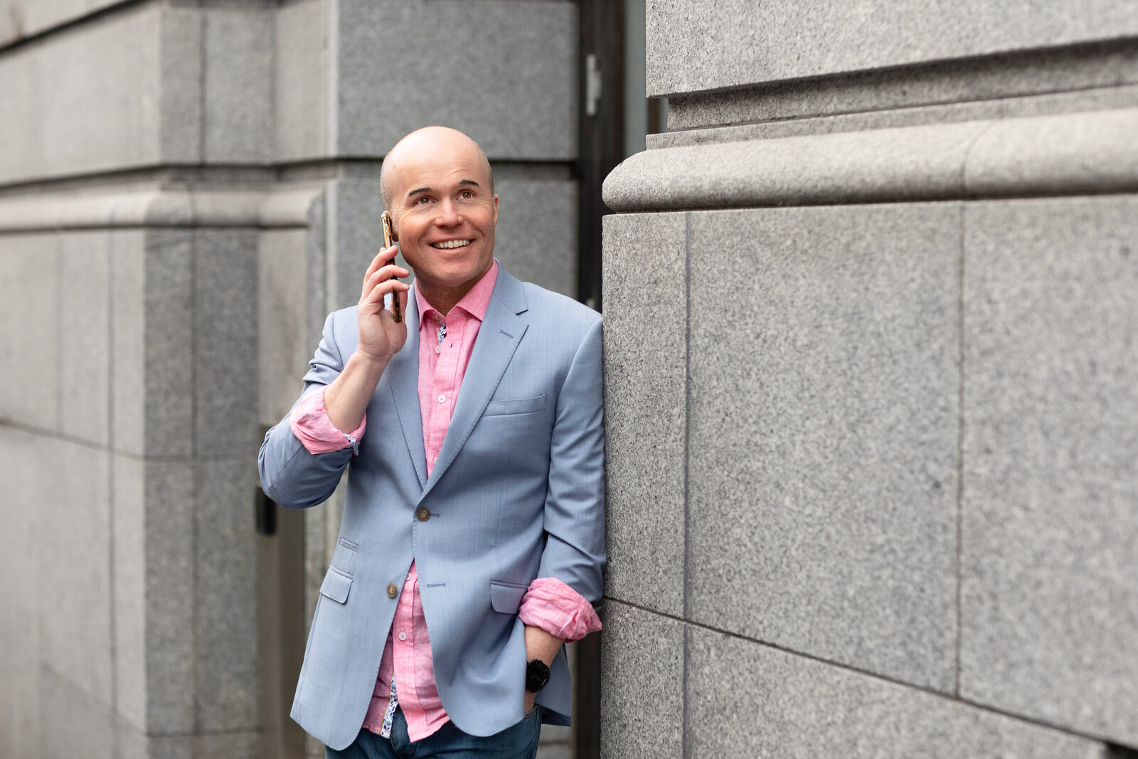 A business man leaning against building wall talking on his mobile