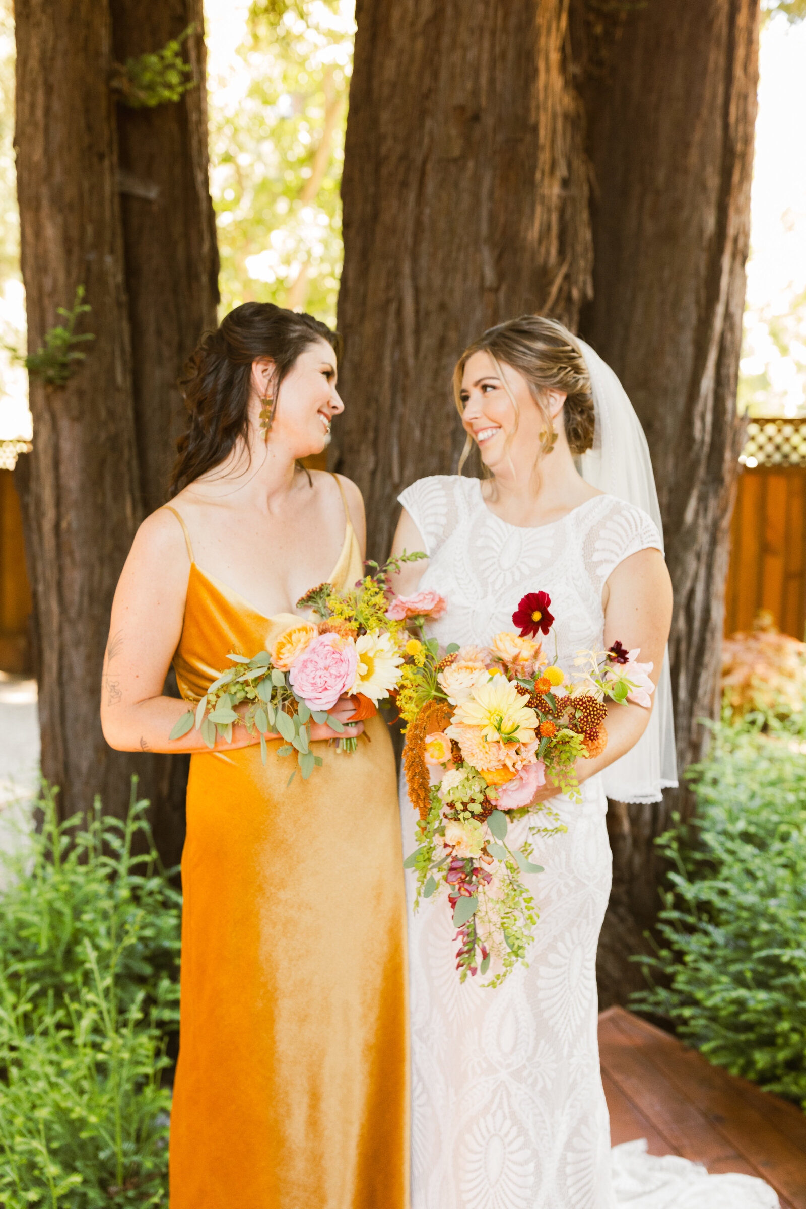 Bride and bridesmaid at her colorful wedding ceremony in Santa Cruz, California in the redwood trees.