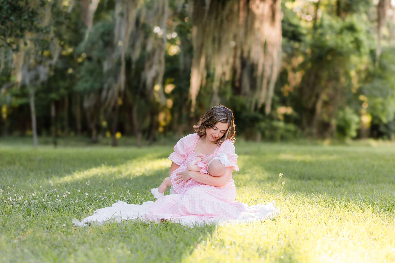 Young mom wearing a pink dress holding her baby girl with love in her eyes