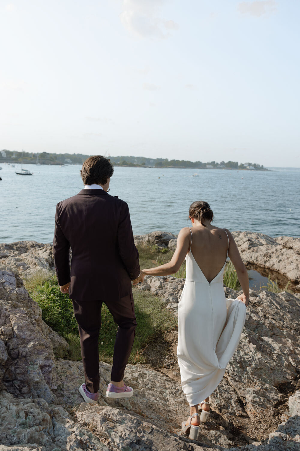 Bride and groom walking hand-in-hand by the seaside