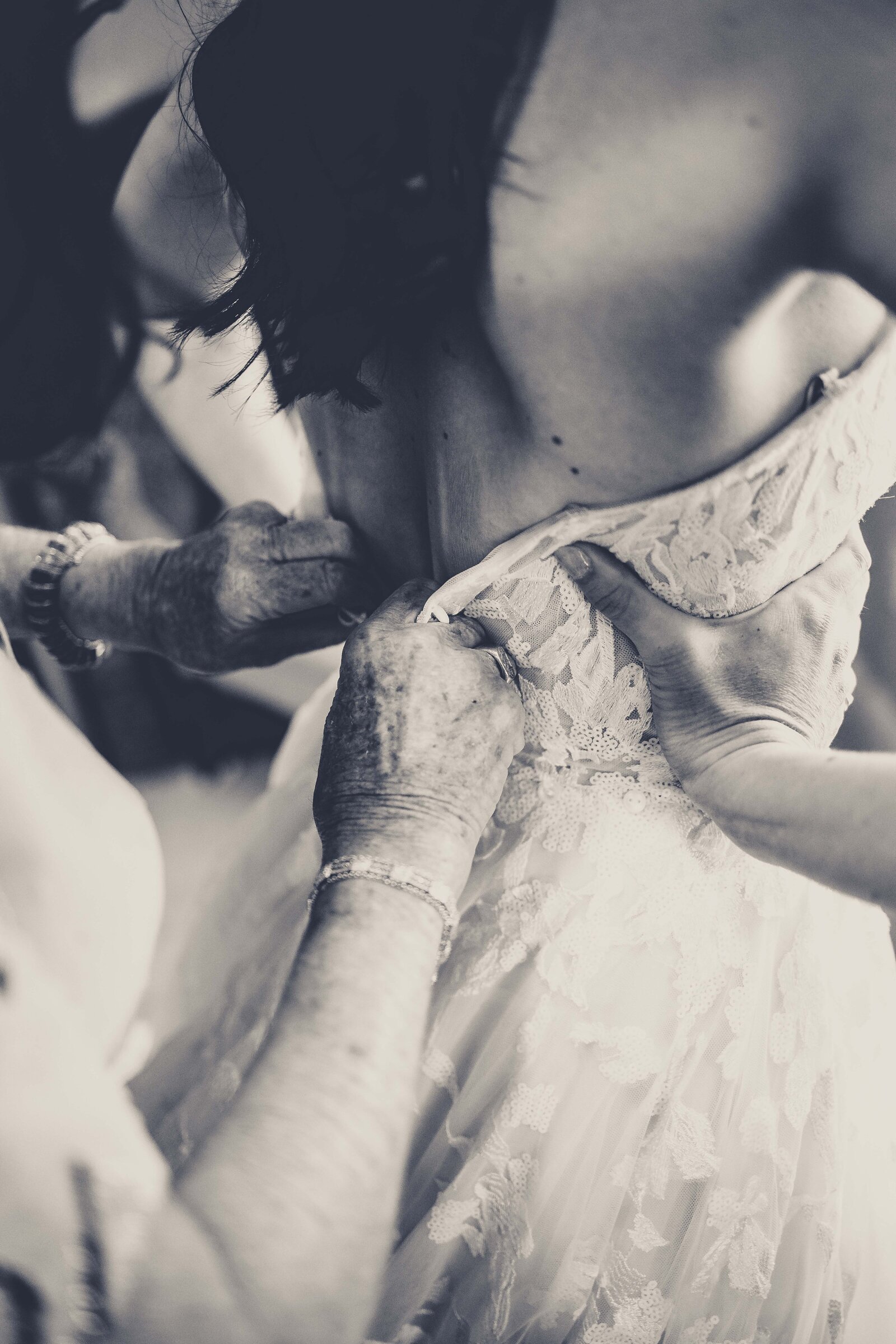 Witness a poignant and heartwarming moment as a mother carefully zips up her daughter's wedding dress, symbolizing the emotional bond and support on this significant day. Captured with tenderness and care, this image showcases the intricate details of the dress and the loving connection between generations. Ideal for those inspired by the intimate family moments that enrich the wedding experience, this photograph highlights the blend of love, tradition, and anticipation that defines a bride’s preparation.