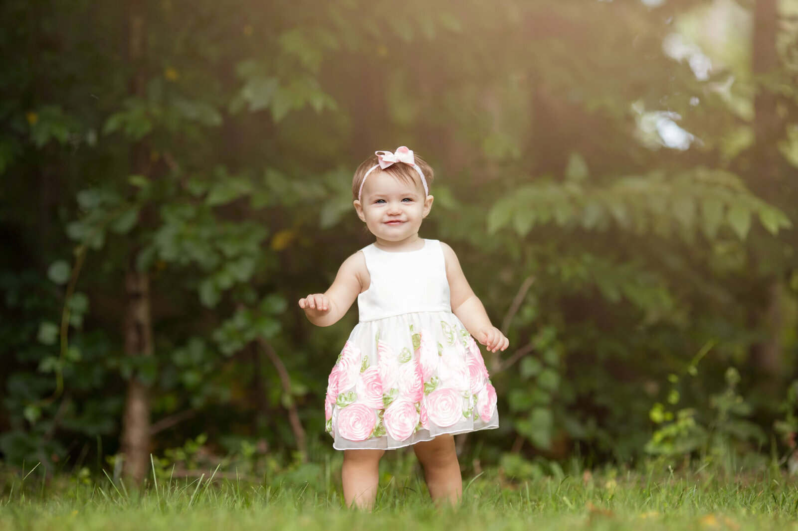 One year birthday photoshoot of little girl wearing a white dress with pink flowers