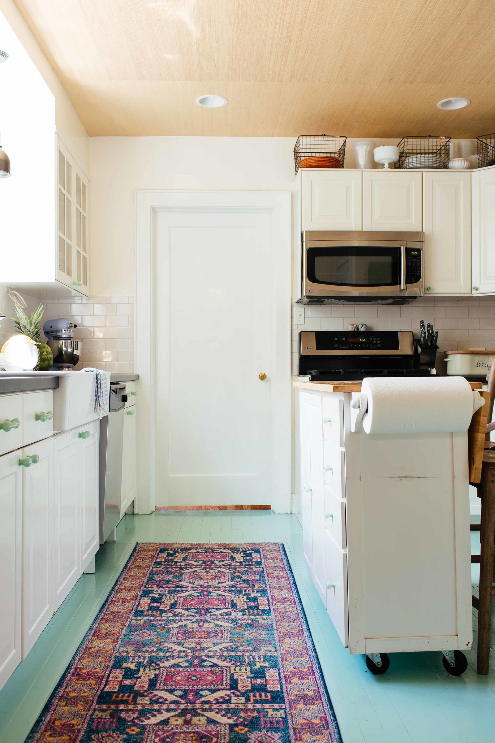 A small kitchen with mint floors and white cabinets.