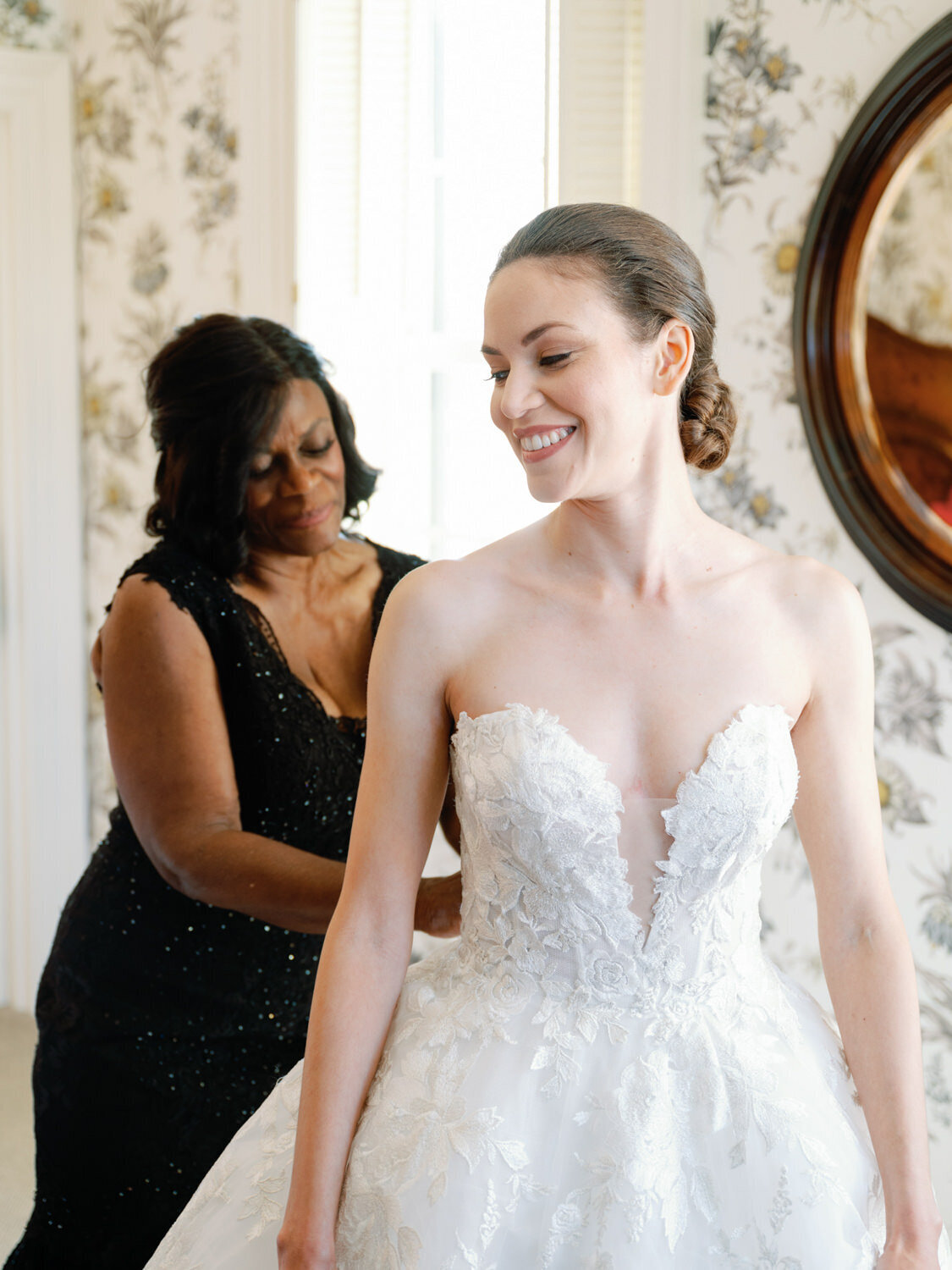 Mom buttoning up her daughter's wedding dress at Inns of Aurora.
