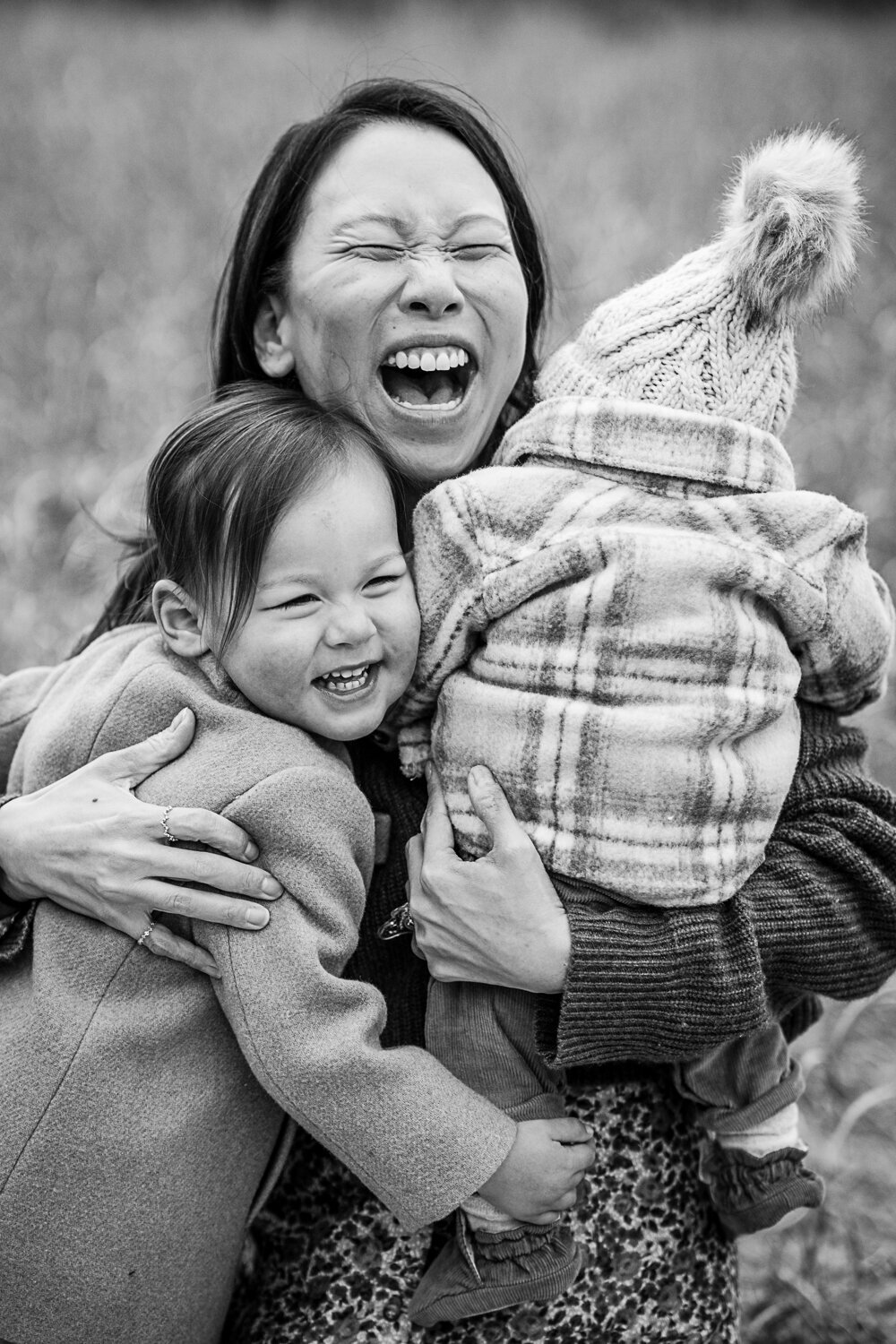 mom holds toddler and infant and laughs