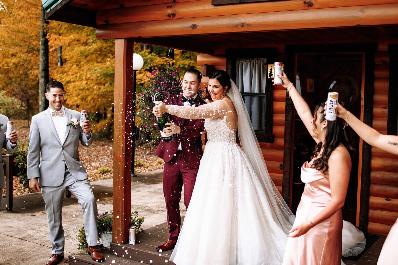 Bride and groom pop a bottle of champagne to  celebrate their marriage