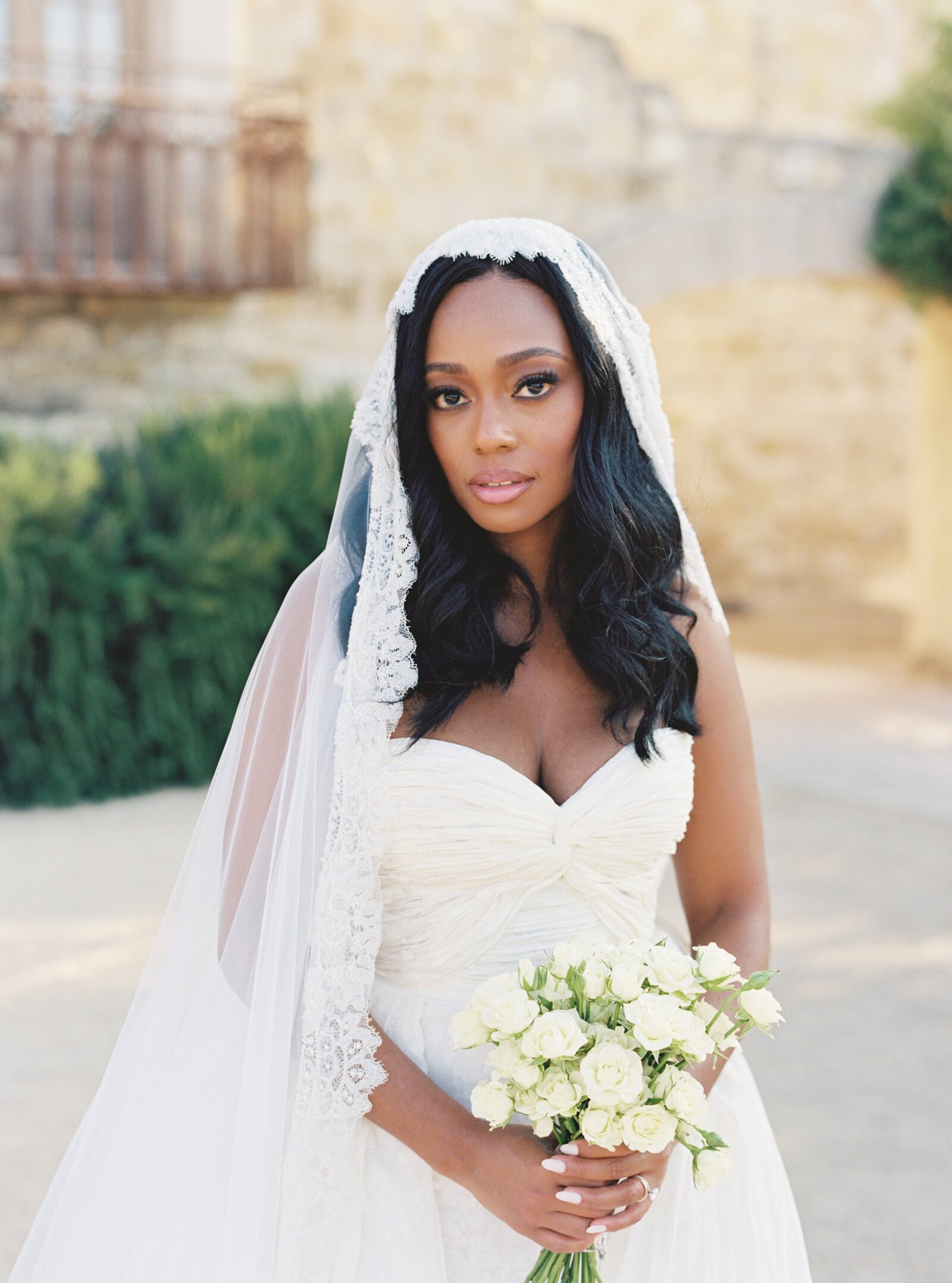 bride holding a bouquet of white flowers and wearing a cathedral veil