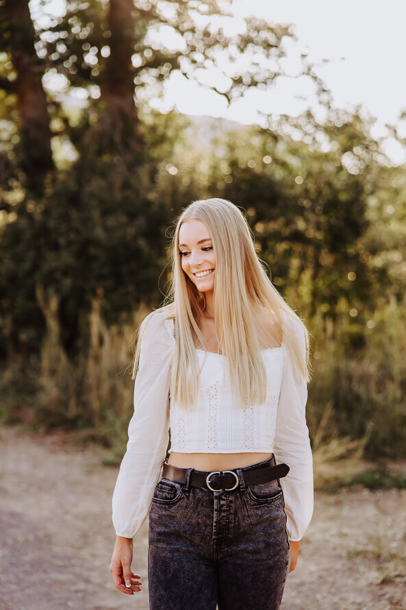 Girl looks down while walking for her senior photos.