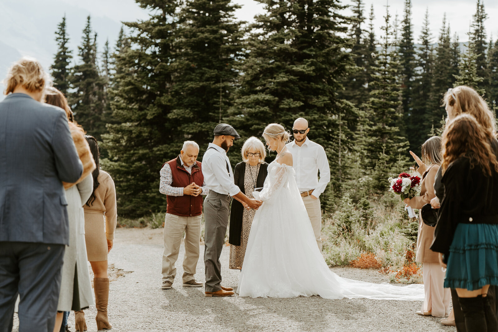 Bride and groom getting married in Mount Rainier National Park with their friends and family praying during their ceremony