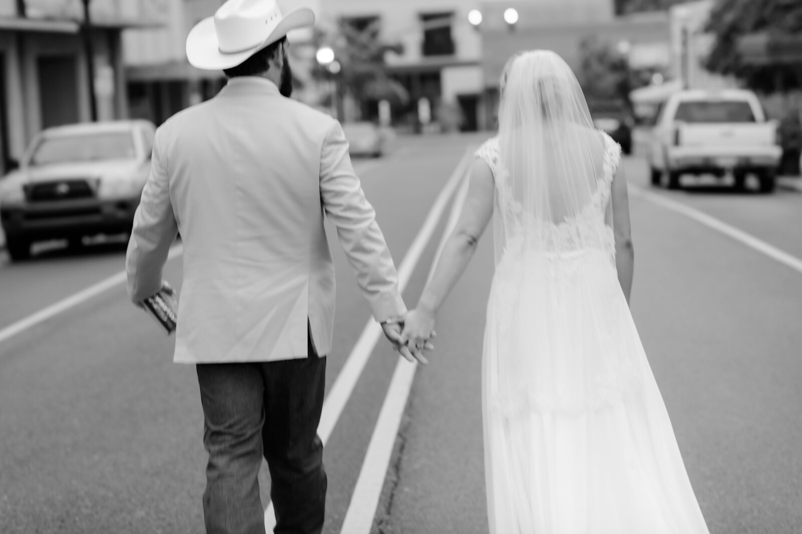 Little Rock wedding photographer captures bride and groom holding hands and walking dow the streets of downtown together