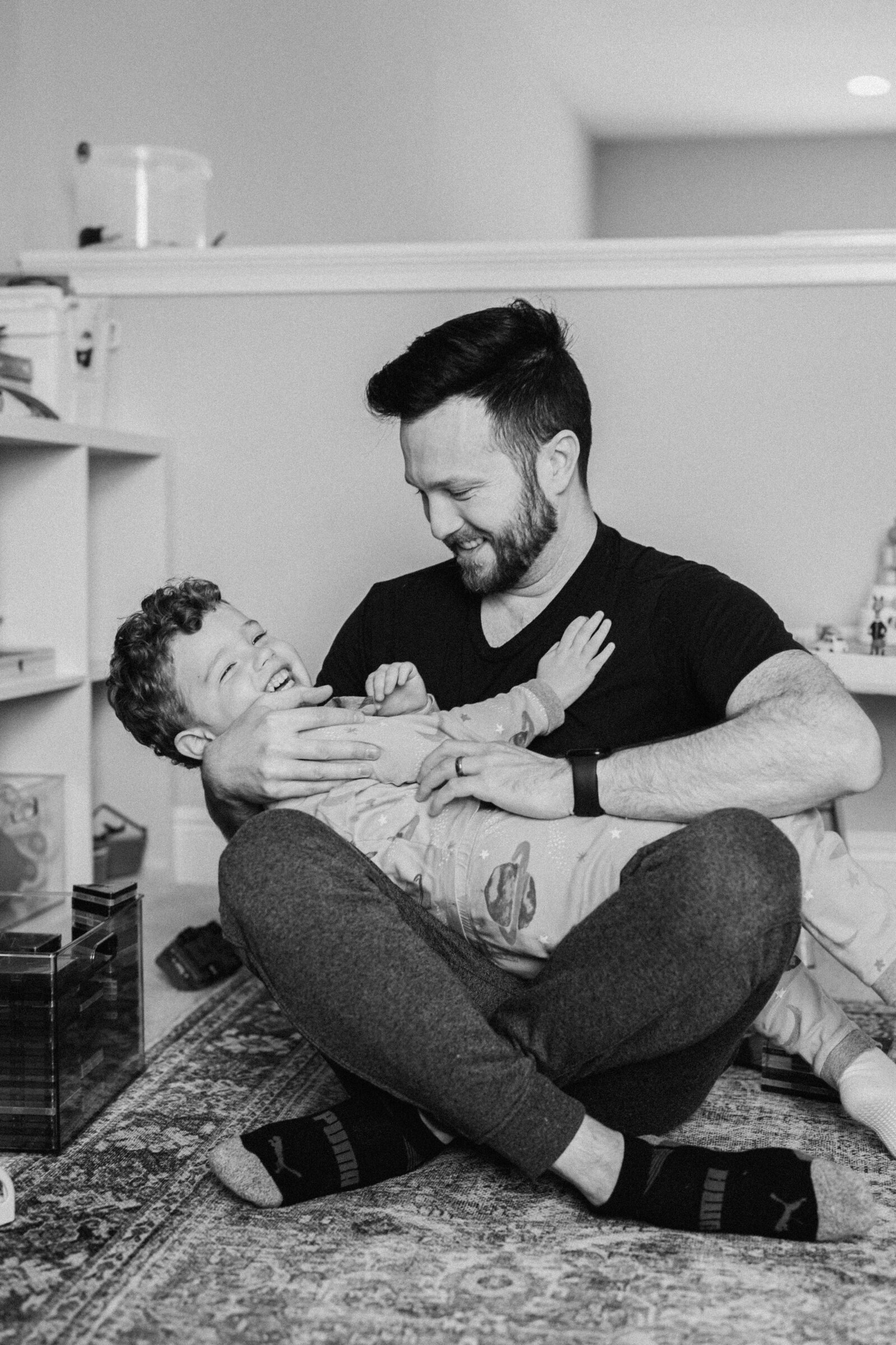Dad holds son in play room while both are laughing