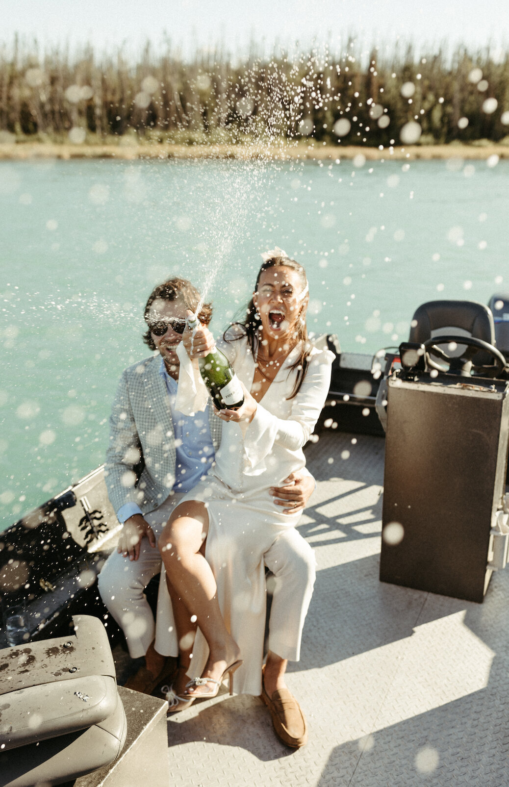 Couple popping champagne after saying I do on a boat