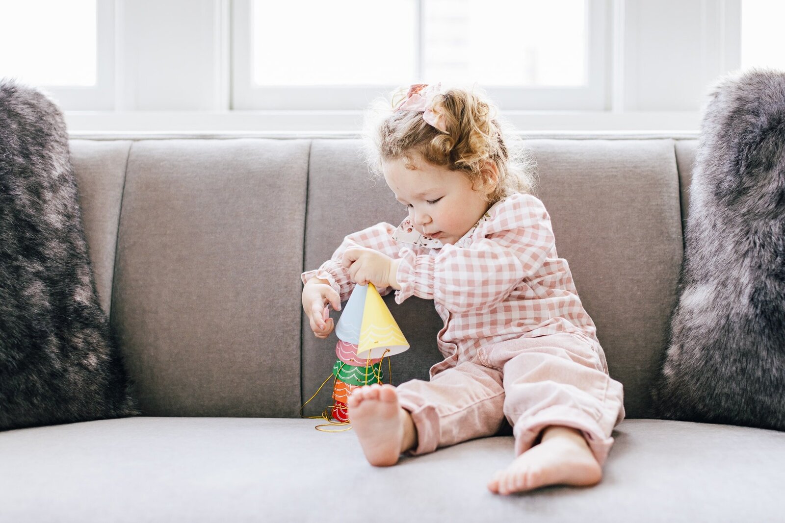 Girl playing with hats on couch