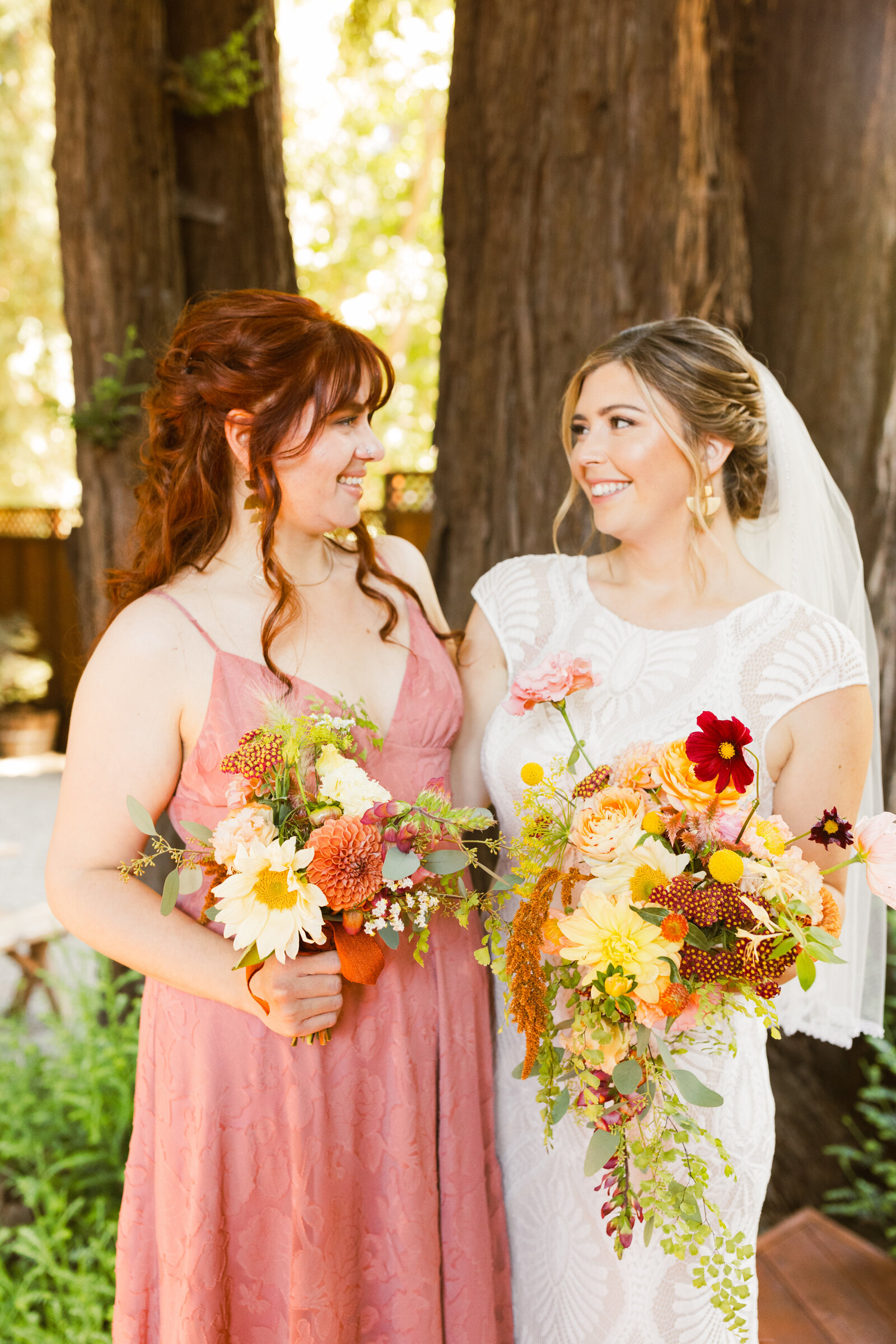 Bride and bridesmaid at her colorful wedding ceremony in Santa Cruz, California in the redwood trees.