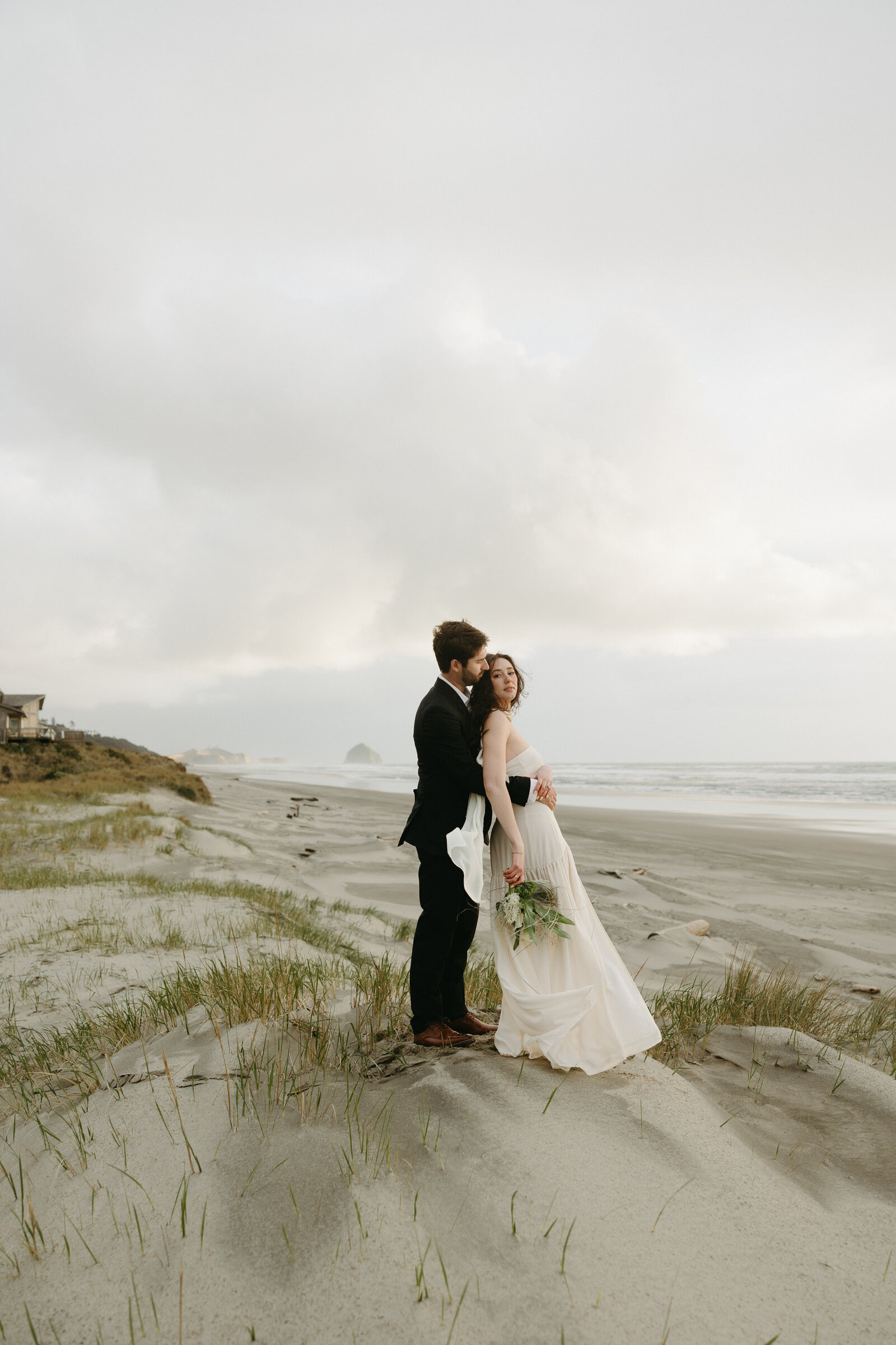 A couple poses for wedding portraits after getting married on a beach in Tofino.