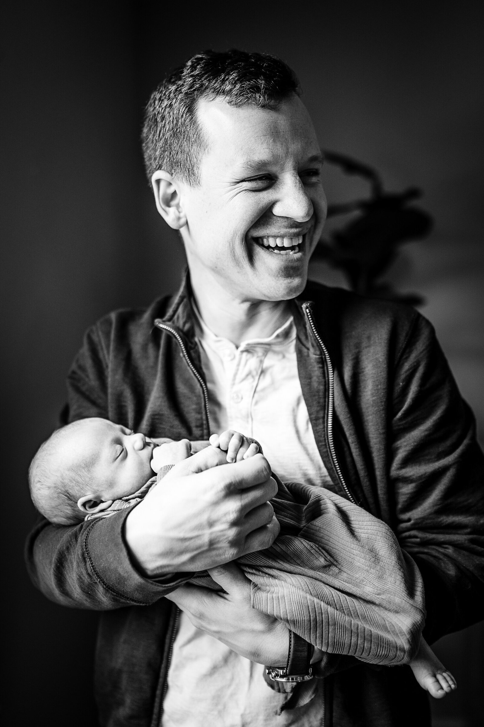 father laughs while holding baby boy